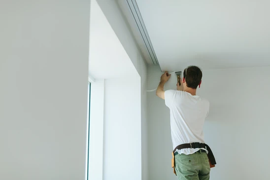 Bâtiment masculin faisant des travaux de finition au plafond dans des appartements, rénovant la maison
