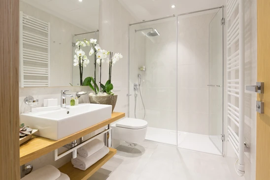 Salle de bains moderne avec douche à l'italienne, vasque rectangulaire sur plan de travail en bois, WC suspendu et sèche-serviettes